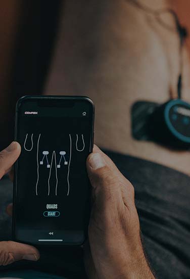 athlete with compex mini wireless on quads looking at app
