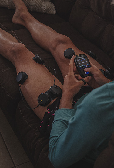 Runner using muscle stimulator sitting on the couch